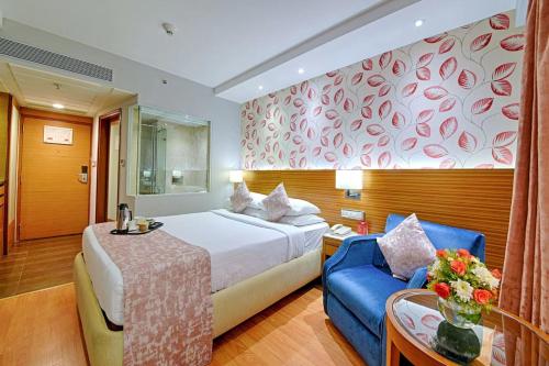 een hotelkamer met een bed en een blauwe bank bij De Sovrani in kolkata