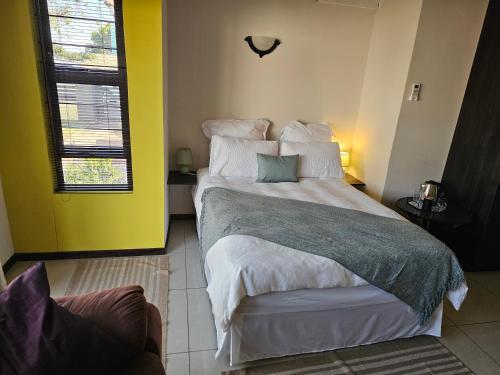 a bedroom with a large bed and a yellow wall at Cora's Boutique Bed & Breakfast in Swakopmund
