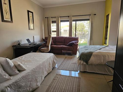 a bedroom with two beds and a desk and a couch at Cora's Boutique Bed & Breakfast in Swakopmund