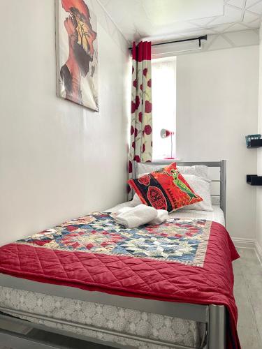 a bedroom with a bed with a red quilt at Westfield Gardens - 3 Bedroom Apartment in Goodmayes