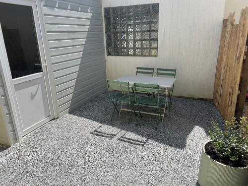 d'une terrasse avec une table, des chaises et une porte. dans l'établissement appartement 50 mètres de la mer, à Jullouville
