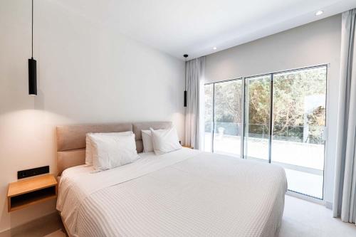 a bedroom with a white bed and a large window at Villa Lazareto in Kontokali