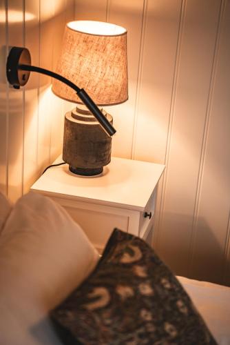 a lamp on a night stand next to a bed at Två Skyttlar in Örby
