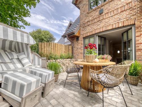 a patio with chairs and a table and a brick building at Südwind's Deichperle in Westerland (Sylt)