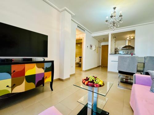 sala de estar con TV y mesa con fruta. en Jardines de Denia 24, en Denia