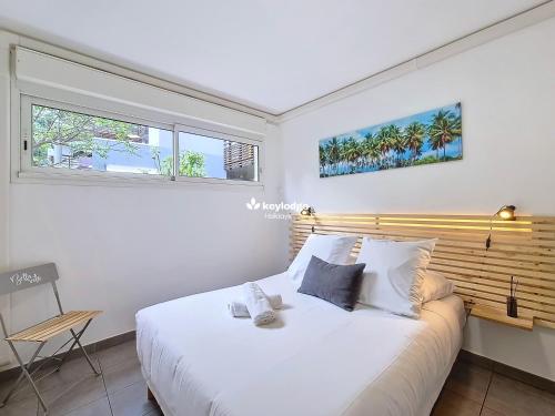 a bedroom with a large white bed and two windows at Douceur Exotique - 2 chambres - piscine partagée - centre-ville de Saint-Pierre in Saint-Pierre