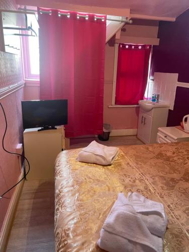 a room with a bed and a tv and red curtains at Jewel Of The Sea Hotel in Blackpool