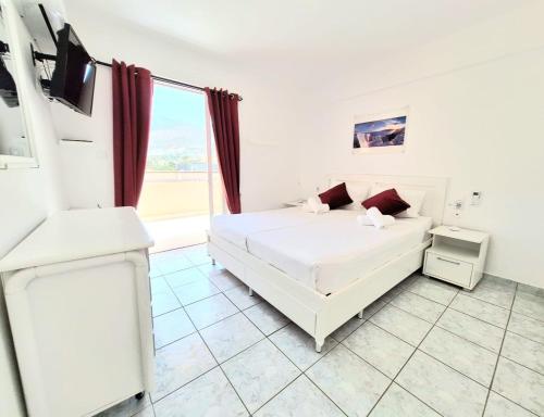 a white bedroom with a bed and a large window at Domus Dulcis Domus in Hersonissos