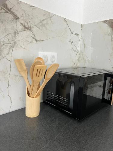 un récipient d'ustensiles en bois à côté d'un micro-ondes dans l'établissement Appartement AN-Lux, à Saint-Louis