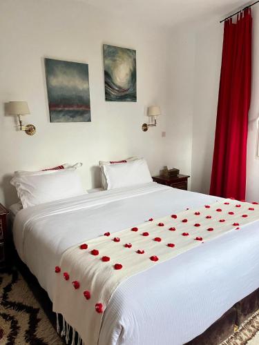 a bedroom with a large white bed with red roses on it at RIAD OASIS D'ASILAH in Asilah