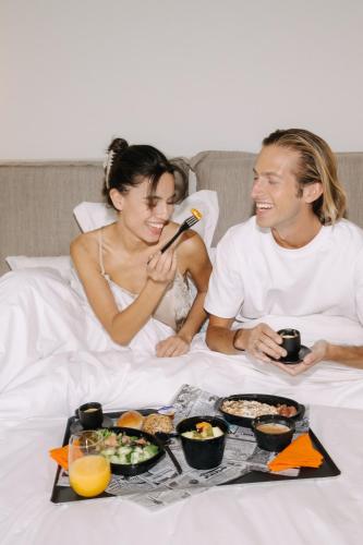 Een man en een vrouw in bed met een dienblad eten. bij Airio Athens Suites in Athene