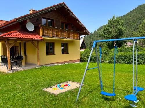 a playground in a yard with a house at Chata Ski Chopok in Belá