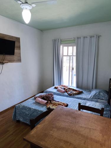 a bedroom with two beds and a table and a window at Residencial María in Bombinhas
