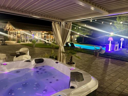 a jacuzzi tub on a patio with a pool at night at Family Relais La Magnolia in Villanova dʼAsti