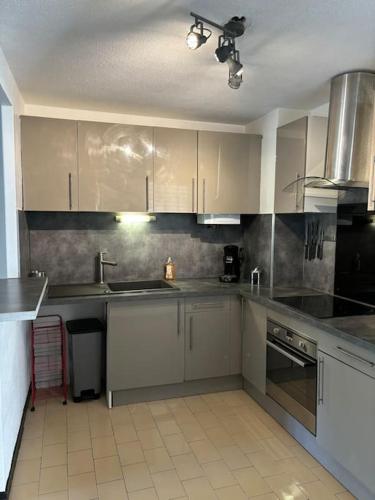 une cuisine avec des armoires blanches et des appareils en acier inoxydable dans l'établissement CAP proche naturiste, au Cap d'Agde