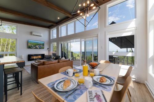 a dining room and living room with large windows at Oasis by the River in Saint-Irénée