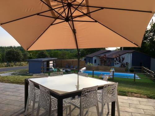 une table et des chaises avec un parasol sur une terrasse dans l'établissement Maison entière location tourisme quatre étoiles proche de sites touristiques, à Le Roc