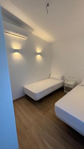 a white room with two beds and two lights at Casa de huéspedes Arroyo Bujías - 3 habitaciones con baño privado individual in Alora