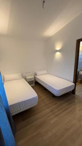 two beds in a room with white walls and wooden floors at Casa de huéspedes Arroyo Bujías - 3 habitaciones con baño privado individual in Alora
