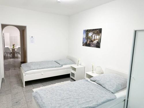 ein weißes Zimmer mit zwei Betten und einem Spiegel in der Unterkunft Work and Stay Apartment in Troisdorf in Troisdorf