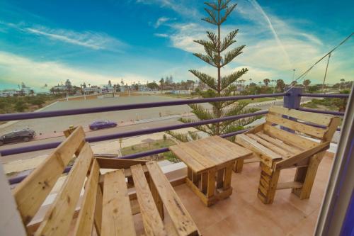 a picnic table and bench on a balcony with a view of the beach at Duplex Oualidia surfhouse in Oualidia