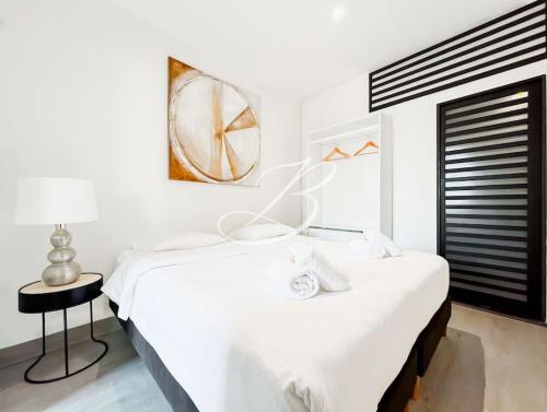 une chambre blanche avec un grand lit et une table dans l'établissement Le Félix Faure - Palais Centre Cannes, à Cannes