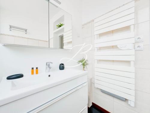 une salle de bain blanche avec un lavabo et un miroir dans l'établissement Le Félix Faure - Palais Centre Cannes, à Cannes