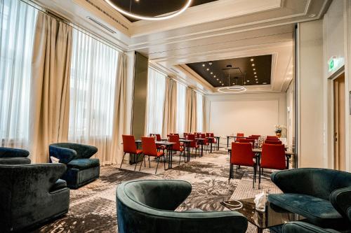 a dining room with red chairs and a table at Steigenberger Icon Parkhotel Düsseldorf in Düsseldorf