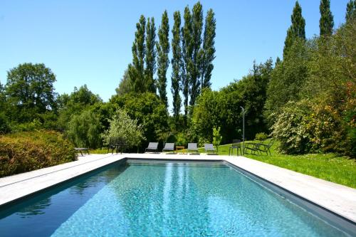 - une piscine avec 2 chaises et des arbres dans l'établissement Beauchamps Maison d'hotes, à Genneville