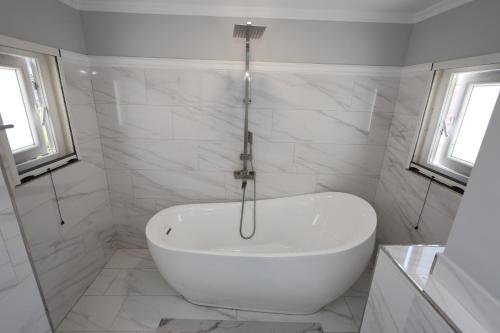 a white tub in a bathroom with white tiles at Villa Lejzo - Swimming Pool in Berat