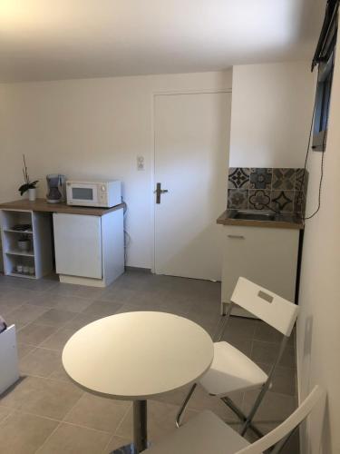 - une table et des chaises blanches dans une chambre avec cuisine dans l'établissement Chambre avec entrée indépendante à La Canourgue, à La Canourgue