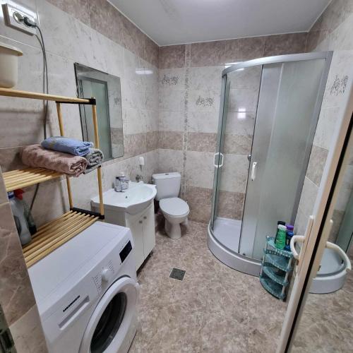 a bathroom with a shower toilet and a washing machine at Apartament Madalina cu 2 dormitoare si vedere spre Dunare in Corabia