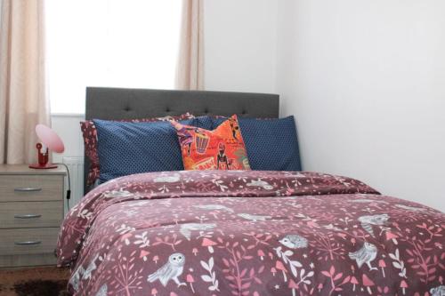a bedroom with a bed with a red comforter at Bowery Apartment - 2 Bedrooms 1st floor in Dagenham