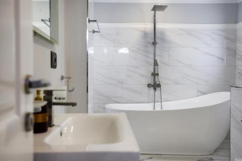 a white bathroom with a tub and a sink at Villa Lejzo - Swimming Pool in Berat