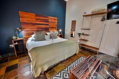 a bedroom with a large bed with a wooden headboard at Blue Rain Guest House in Bloemfontein
