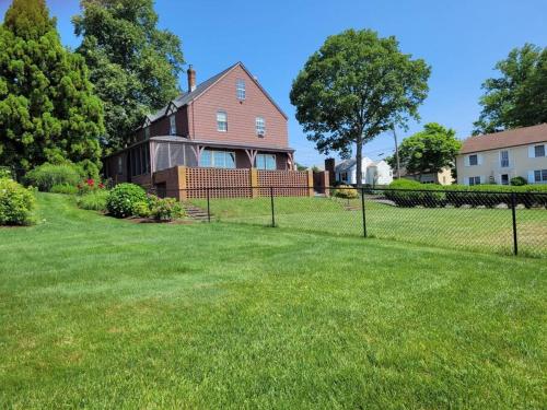 a fence in front of a house with a yard at On the Water Spacious Comfortable Historic House in West Haven