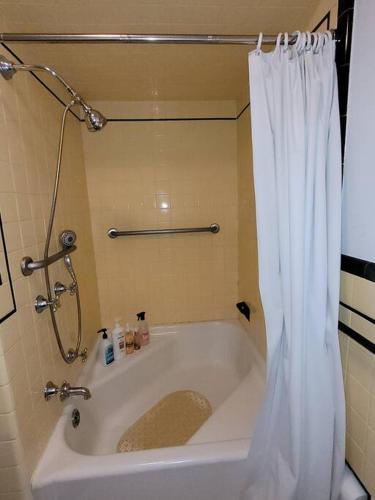 a bath tub with a shower and a white shower curtain at On the Water Spacious Comfortable Historic House in West Haven