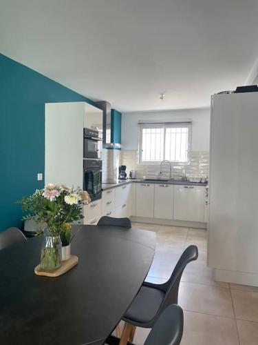 - une cuisine avec une table, des chaises et un vase de fleurs dans l'établissement La moderne Villa Proche Luma, à Arles