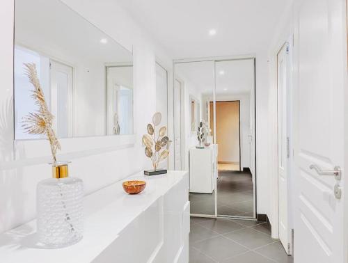 - une salle de bains blanche avec un comptoir et un miroir dans l'établissement Le Marne - Logement CozyTerrasse, à Cannes