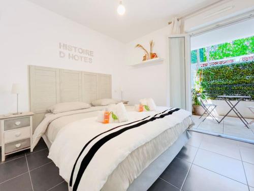 une chambre avec un grand lit et une grande fenêtre dans l'établissement Le Marne - Logement CozyTerrasse, à Cannes