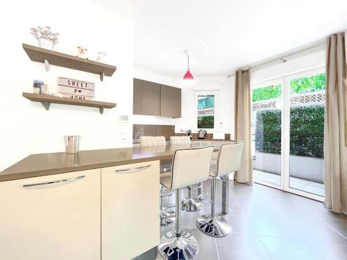 une cuisine avec des armoires blanches et un comptoir avec des tabourets dans l'établissement Le Marne - Logement CozyTerrasse, à Cannes