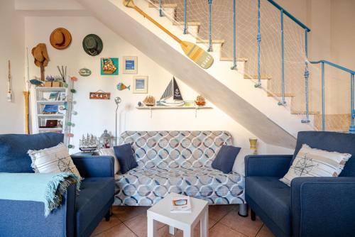un salon avec des canapés bleus et un escalier dans l'établissement Villa Corallina Relais & Climbing Center, à San Vito Lo Capo