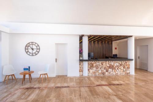 an empty room with a table and chairs and a clock at Comitas Isla del Aire in Punta Prima