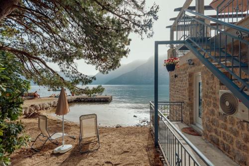 an umbrella and chairs on a beach next to a body of water at Stone sea apartment in Risan
