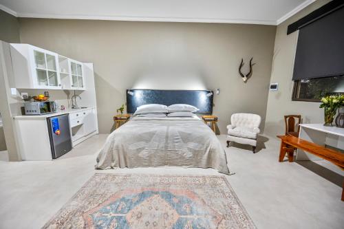 a bedroom with a large bed and a chair at Blue Rain Guest House in Bloemfontein