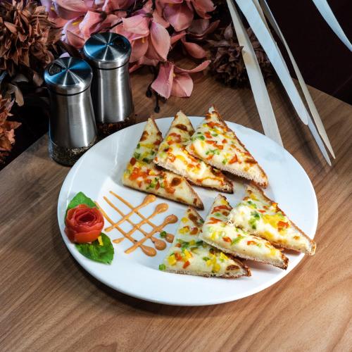 a white plate with slices of pizza on a table at Pride Comfort Dwarka Near Dwarkadhish Temple in Dwarka