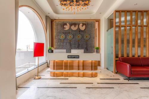 a lobby with a red couch and a chandelier at Pride Comfort Dwarka Near Dwarkadhish Temple in Dwarka