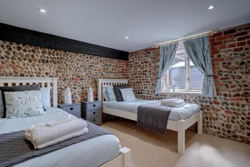 une chambre avec deux lits et un mur de briques dans l'établissement Natterjack by Winterton Cottages, à Winterton-on-Sea
