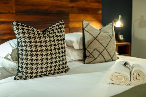 a bed with two pillows and towels on it at Blue Rain Guest House in Bloemfontein