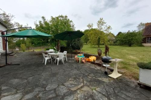 a patio with a table and chairs and an umbrella at Villa le Roche du Ris - 10-12 personnes in Baraize